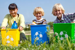 3 children holding small recycling bin.